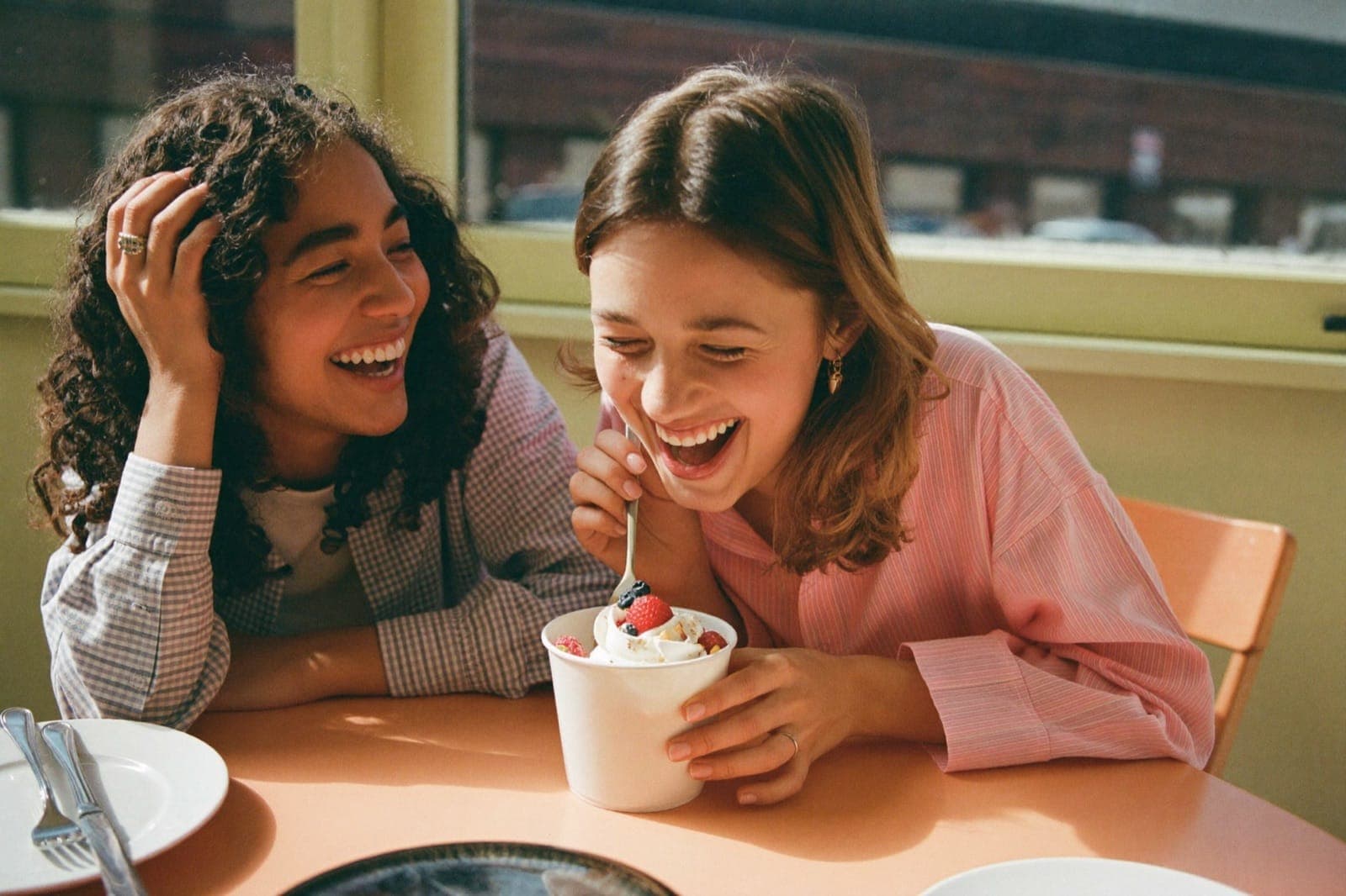 Two friends laughing together while sharing a Frozen Cup dessert